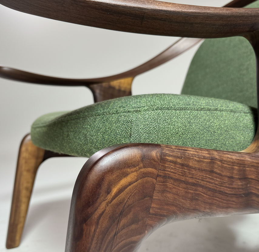 Close-up of a green upholstered chair with wooden armrests on a white background