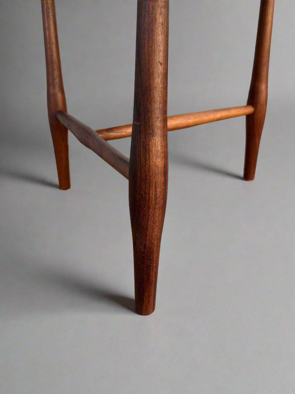 Close-up of a wooden stool leg on a gray background