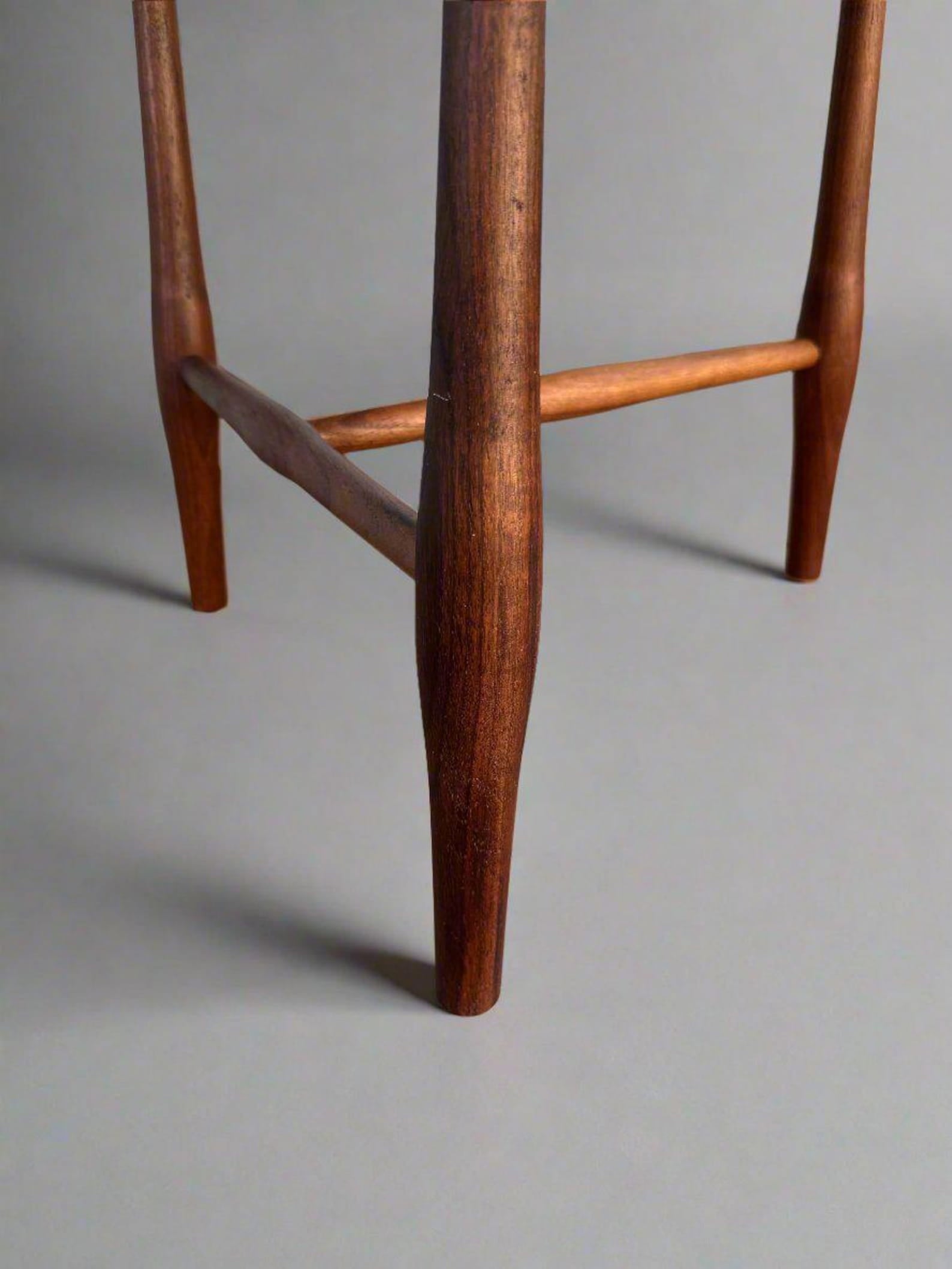 Close-up of a wooden stool leg on a gray background