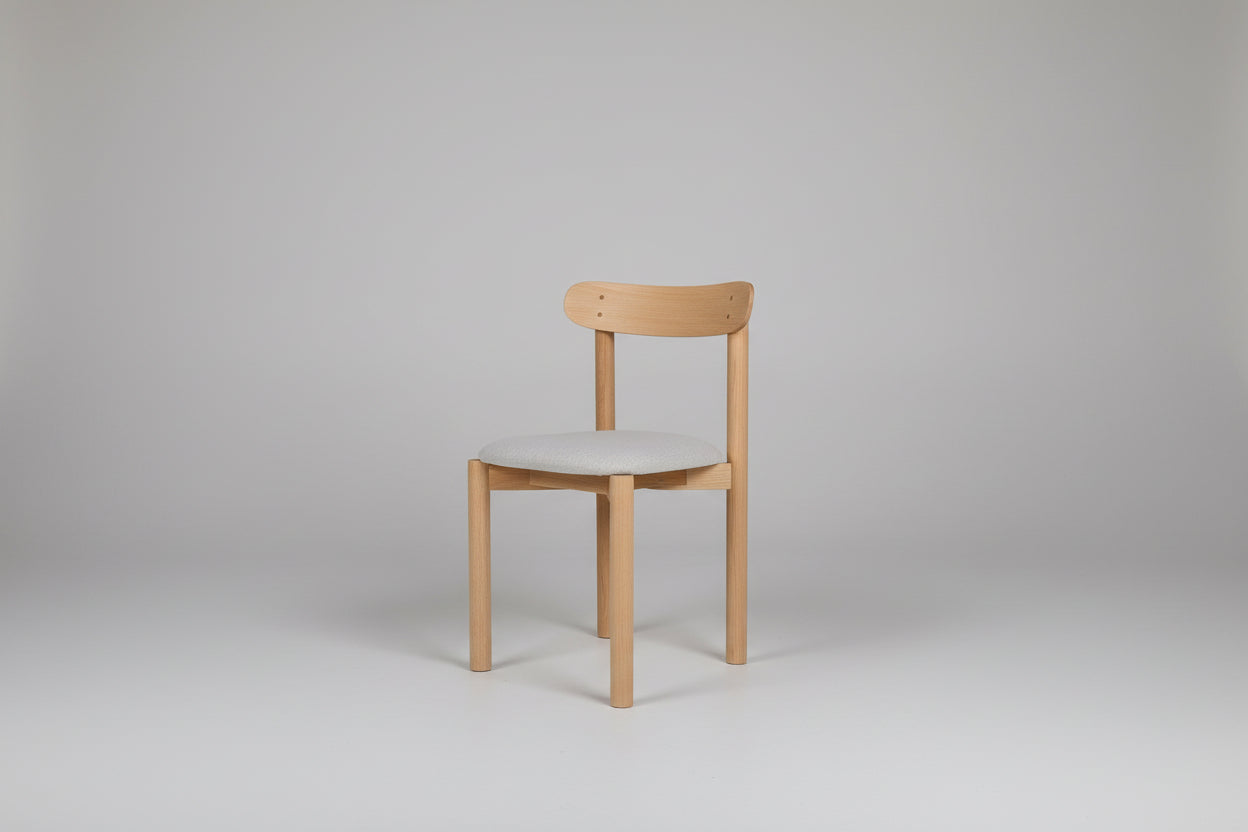 Wooden chair with a white cushion on a green wall and wooden floor.