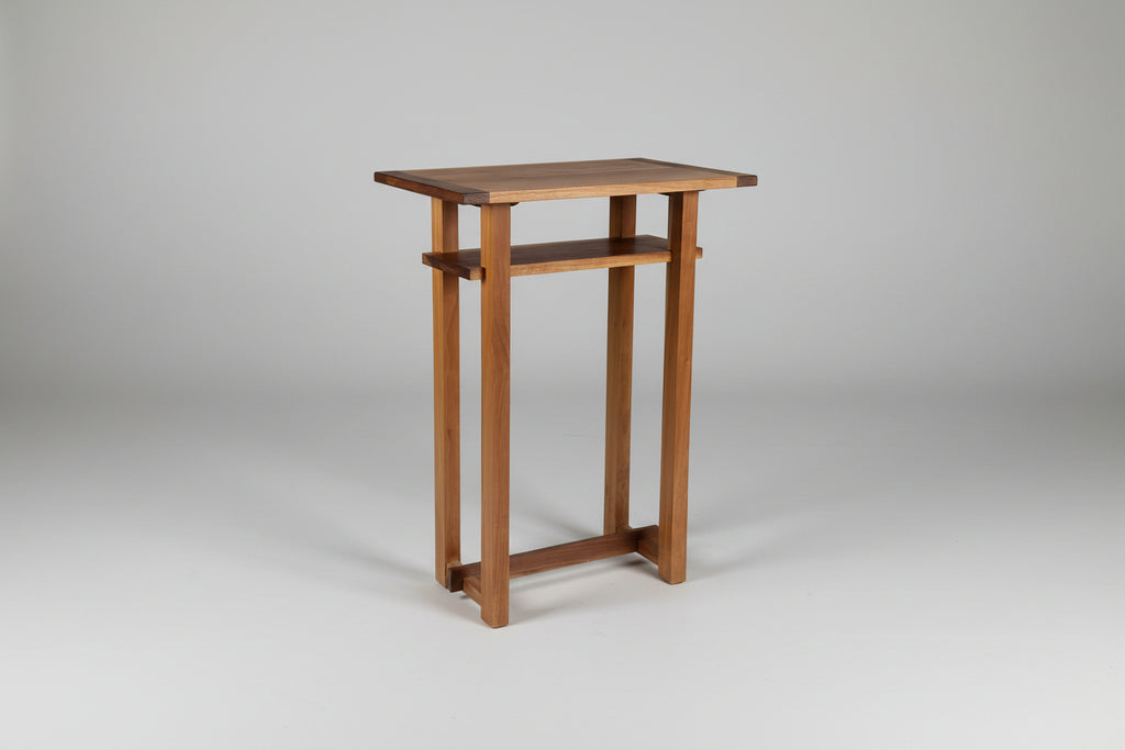 Wooden side table against a white wall on a wooden floor