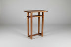 Wooden side table against a white wall on a wooden floor