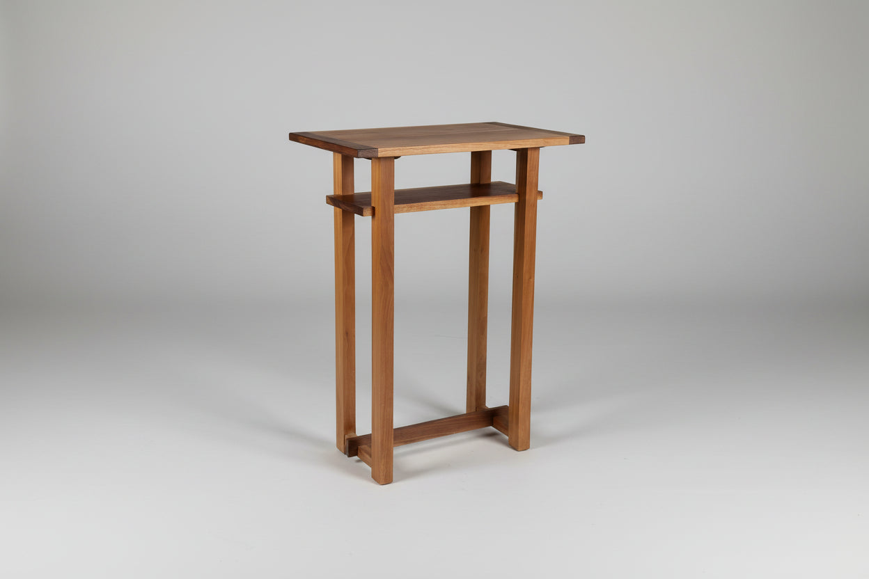 Wooden side table against a white wall on a wooden floor