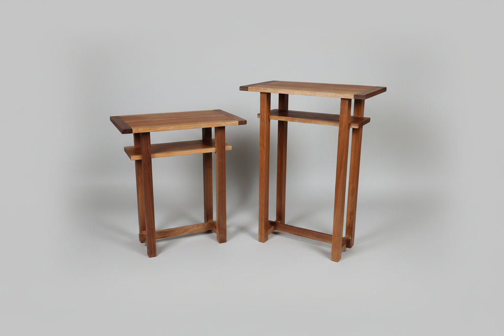 Two wooden side tables on a wooden floor with a white wall in the background.