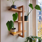 Wooden wall shelf with potted plants against a window with curtains.